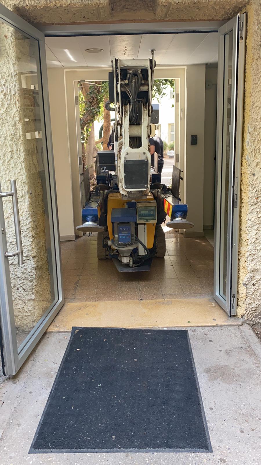 מנוף סל זחלילי עובר בדלת כניסה של מבנה